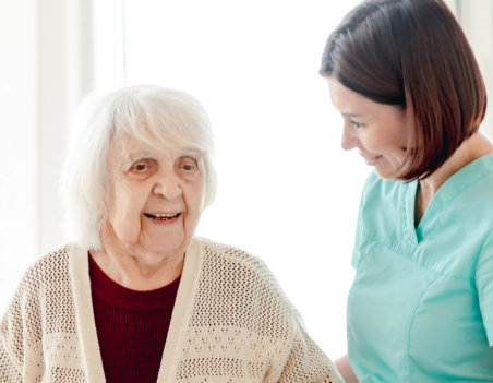 female aide talking to a smiling elderly woman